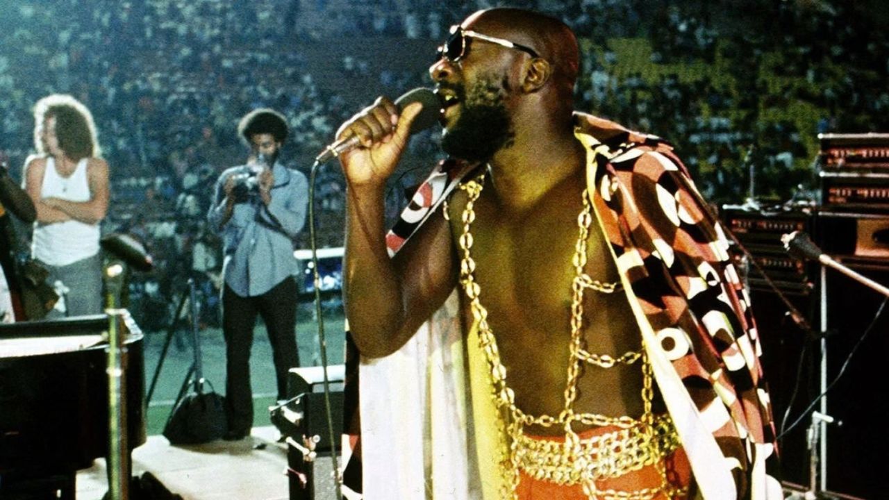 a man with gold chains singing on stage